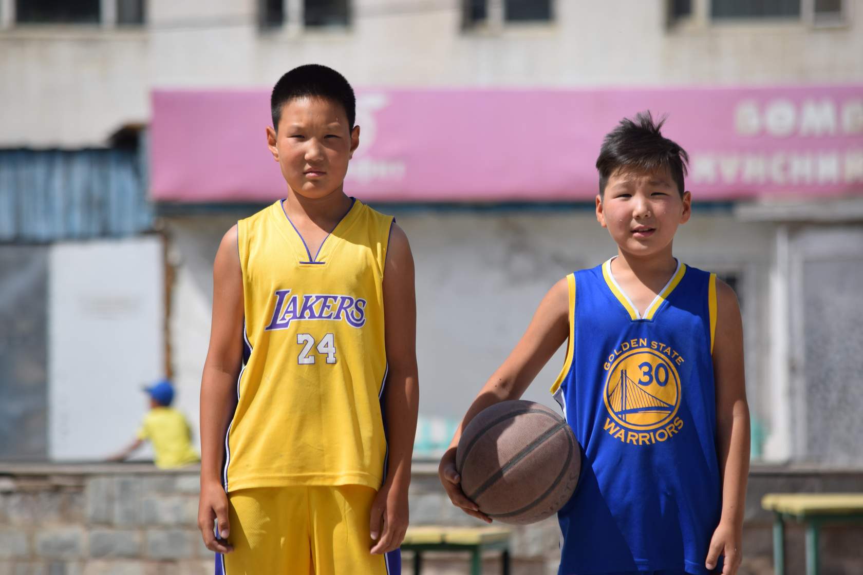 Two boys standing next to each other in basketball uniforms.