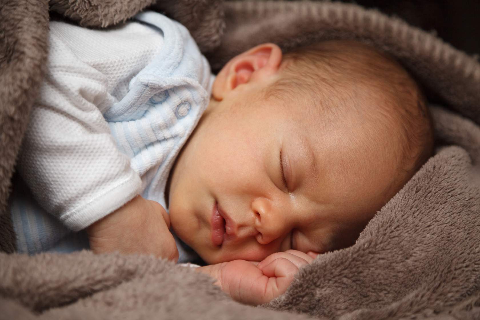 A baby sleeping in a blanket, demonstrating sample psychological functions.