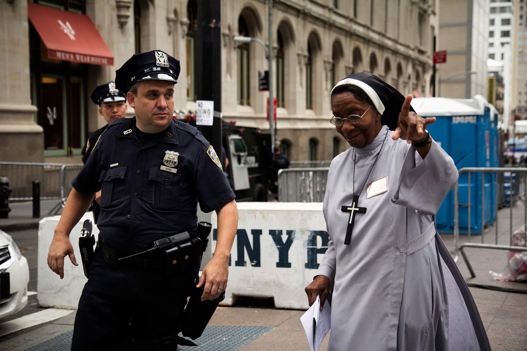 A police officer standing with a nun in a habit during audience control.
