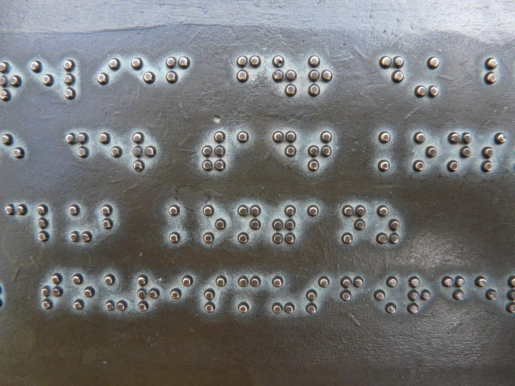 A close up of a metal plate with braille writing.