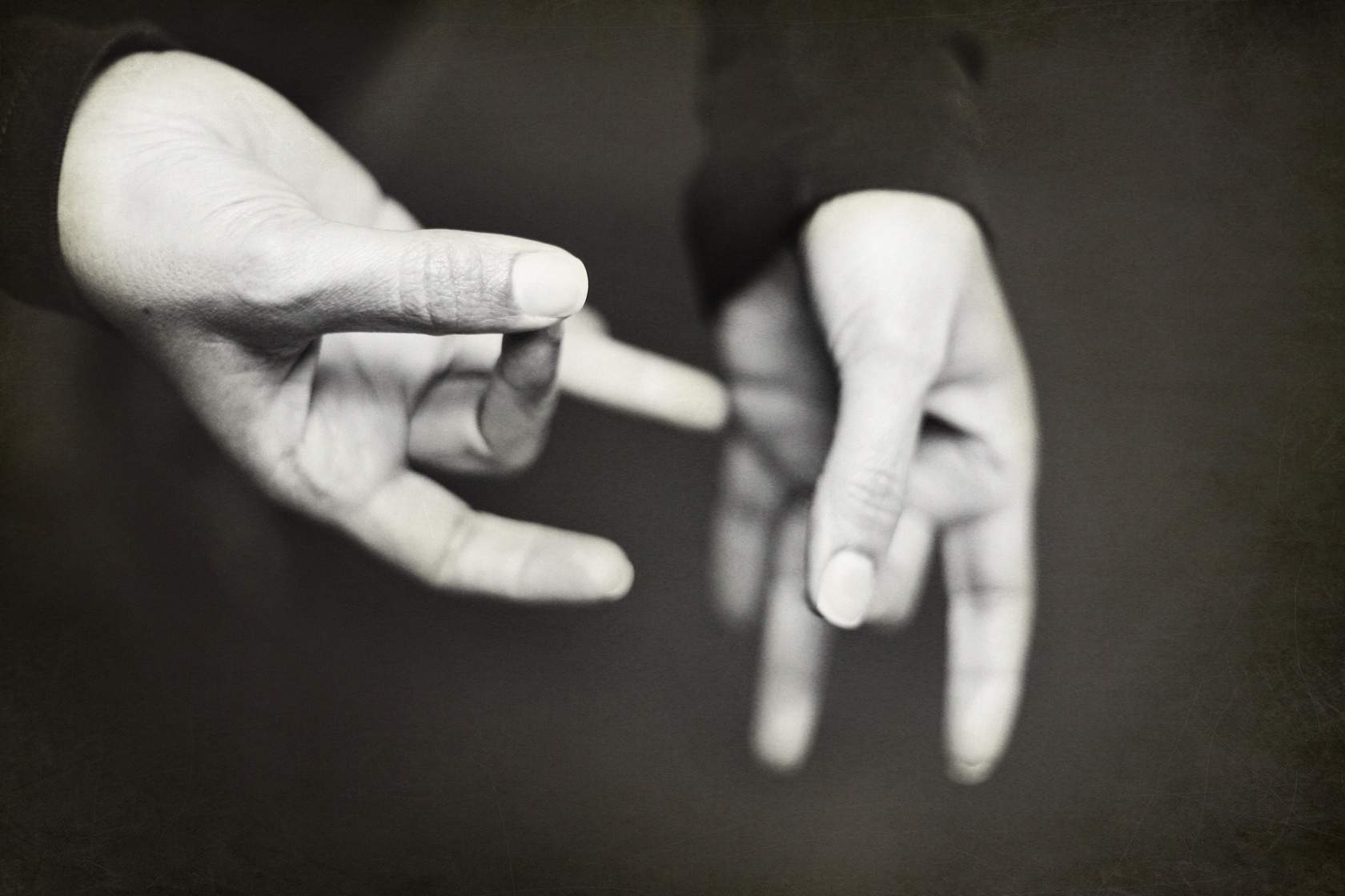 A black and white photo of two hands making a gesture using Sign Language.