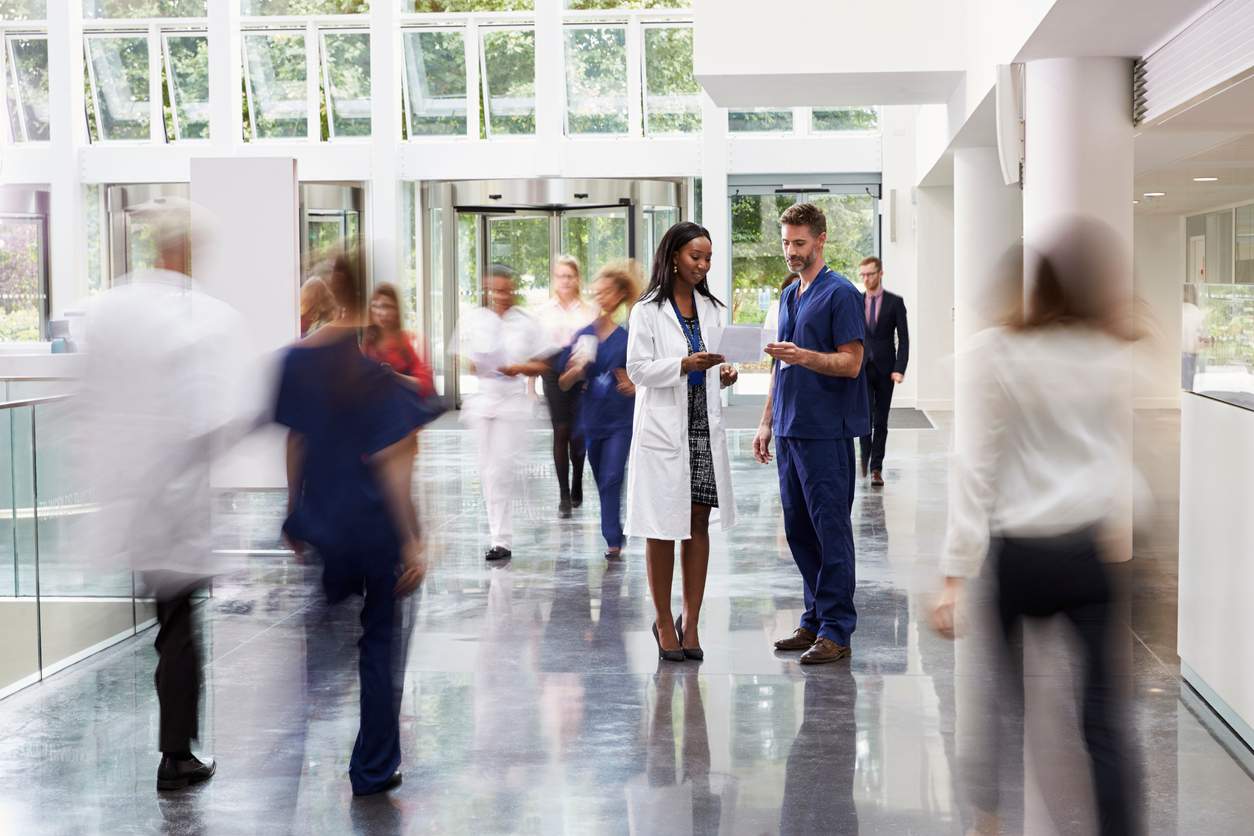 A bunch of individuals strolling through a corridor in a medical center.